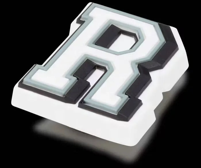 White glow-in-the-dark letter R charm shaped like a Crocs logo, designed to fit into Croc shoe holes.
