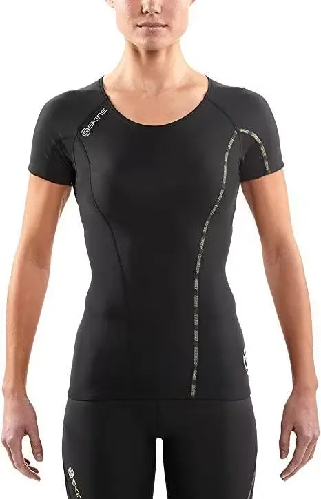 A woman athlete wearing a black SKINS Dnamic Women's Short Sleeve Top, performing a push-up exercise. Close-up of the SKINS Dnamic Women's Short Sleeve Top, highlighting the graduated compression zones and mesh panels. A group of diverse women athletes wearing SKINS Dnamic Women's Short Sleeve Tops in various colors, training together outdoors.