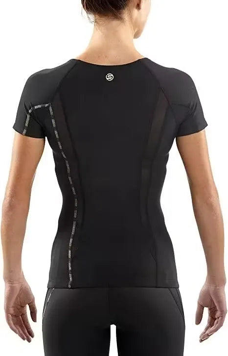 A woman athlete wearing a black SKINS Dnamic Women's Short Sleeve Top, performing a push-up exercise. Close-up of the SKINS Dnamic Women's Short Sleeve Top, highlighting the graduated compression zones and mesh panels. A group of diverse women athletes wearing SKINS Dnamic Women's Short Sleeve Tops in various colors, training together outdoors.