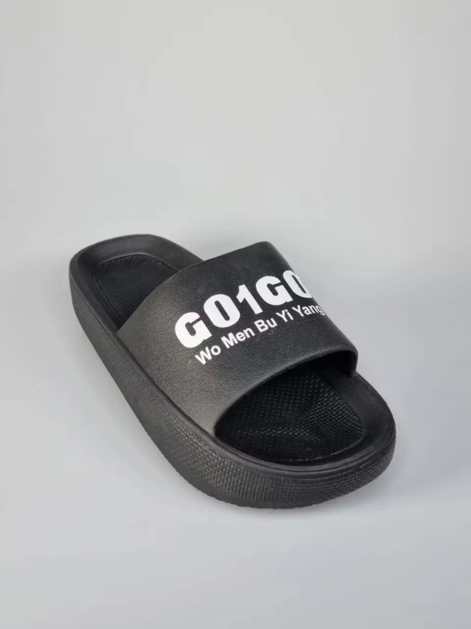 A pair of black unisex slippers with a comfortable-looking design and a unique G01G0 print. The slippers are perfect for both men and women and can be worn for relaxation or running errands.