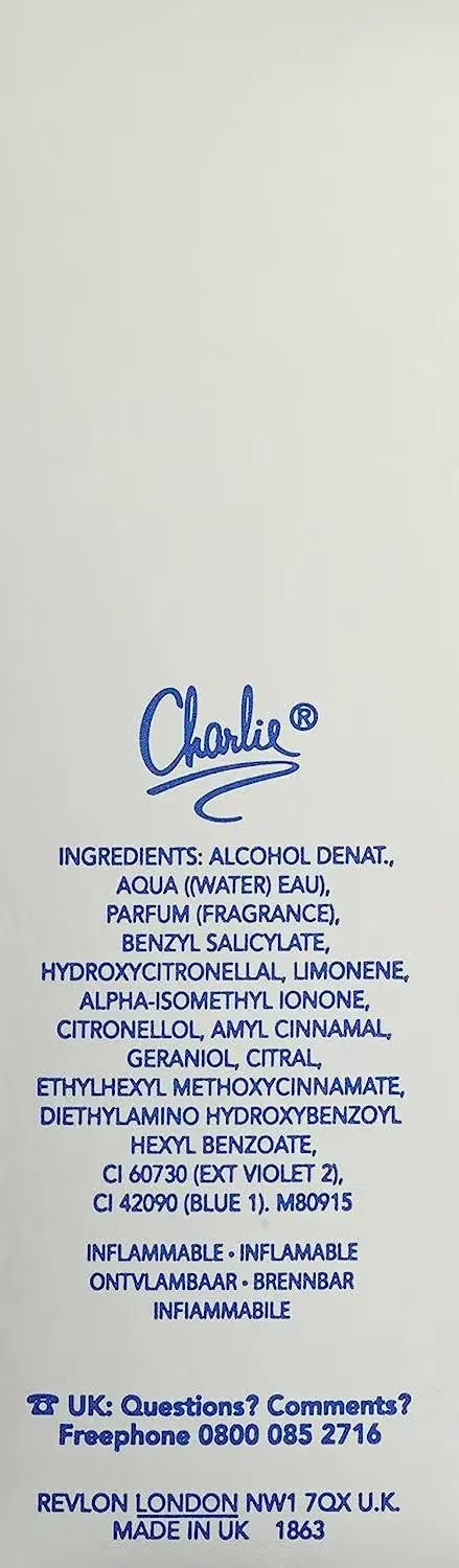 Revlon Charlie Silver Eau De Toilette bottle displayed on a mirrored vanity with soft lighting. Delicate white flowers and a silver pendant add a touch of sophistication.