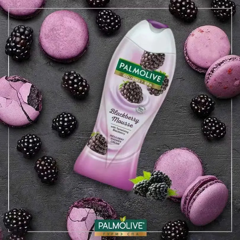 Purple bottle with silver pump dispensing rich, lathery Palmolive Blackberry Shower Gel onto a hand. Blackberries and leaves in the background.