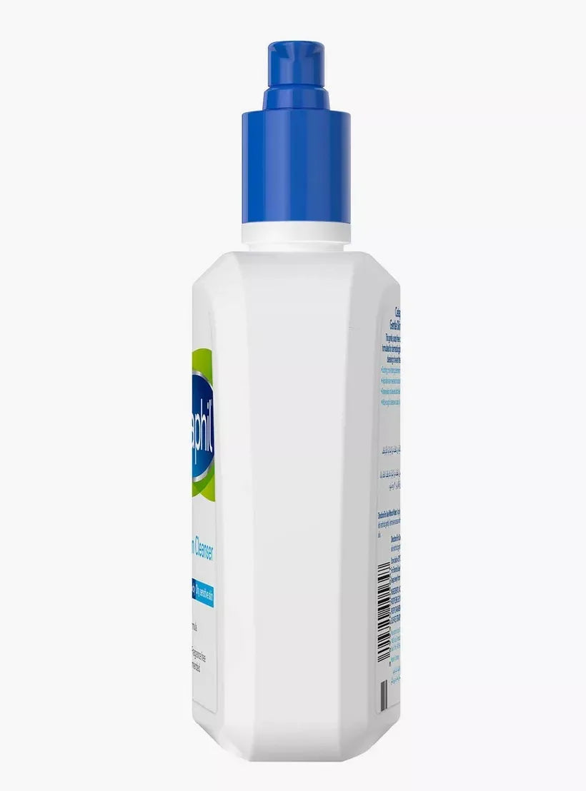 Large white bottle with blue pump dispenser labeled "Cetaphil Gentle Skin Cleanser 500ml." A hand pumps the dispenser, dispensing white cleanser onto another hand.
