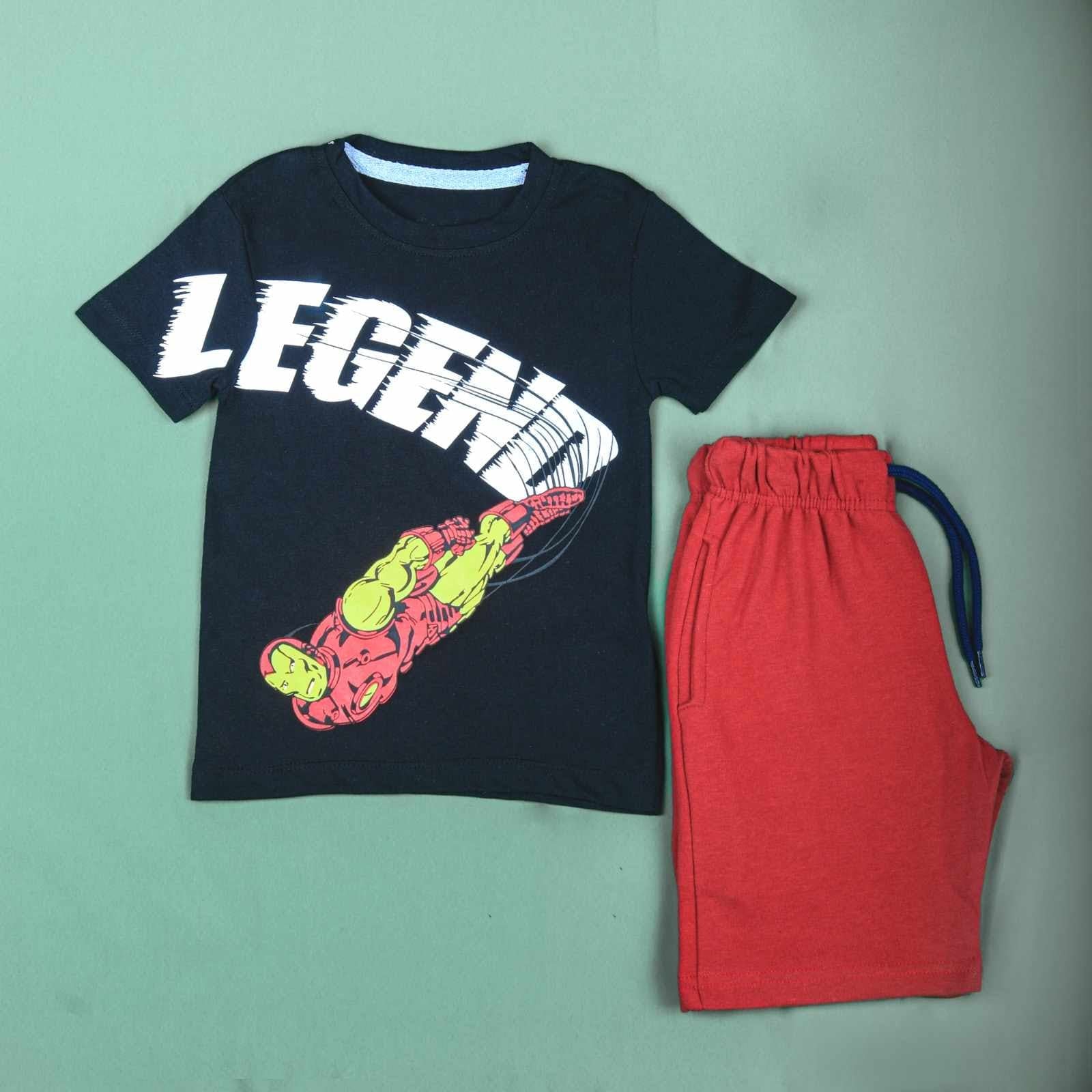 A young boy wearing a black Pebbles Iron Man T-shirt and red shorts, standing confidently with a determined expression.