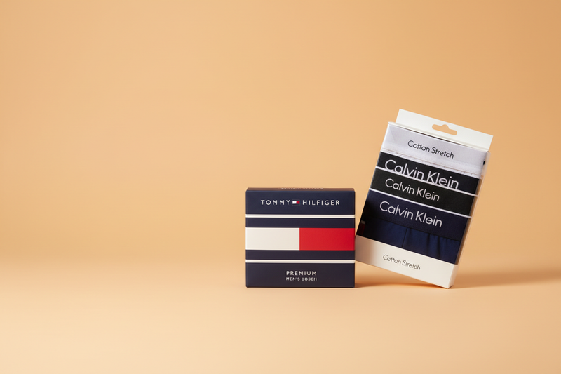 Tommy Hilfiger, Lacoste and Fila men's boxer shorts collection on light orange background