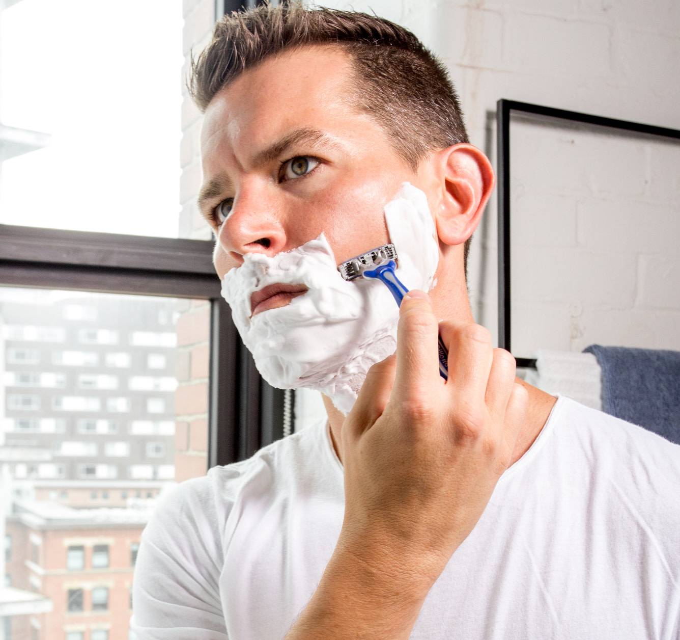 Close-up photo of a blue Gillette Blue3 Comfort Men's Disposable Razor in a 5-pack package. Handle features a soft grip and the image highlights the three blades and lubrastrip.
