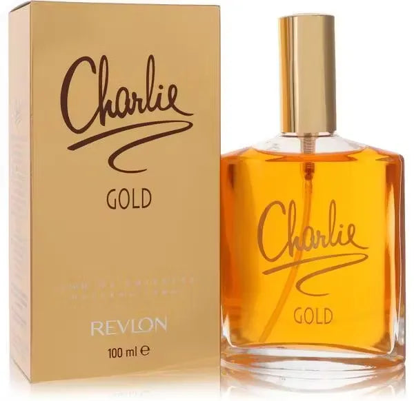 Gold bottle of Revlon Charlie Gold Eau de Toilette perfume on a mirrored vanity with sparkling lights.