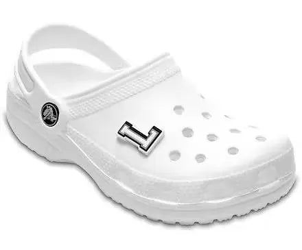 Glow-in-the-dark letter L Jibbitz charm for Crocs shoes. The letter L glows green in the dark. It is attached to a white Crocs shoe with ventilation holes.