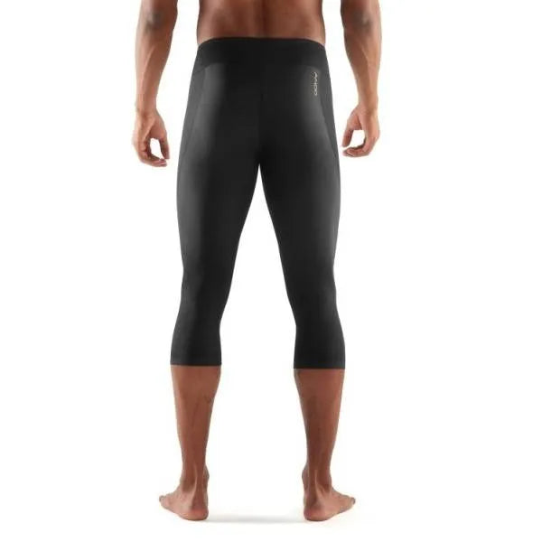A male athlete wearing black Skins A400 3/4 compression tights, mid-stride during a workout.