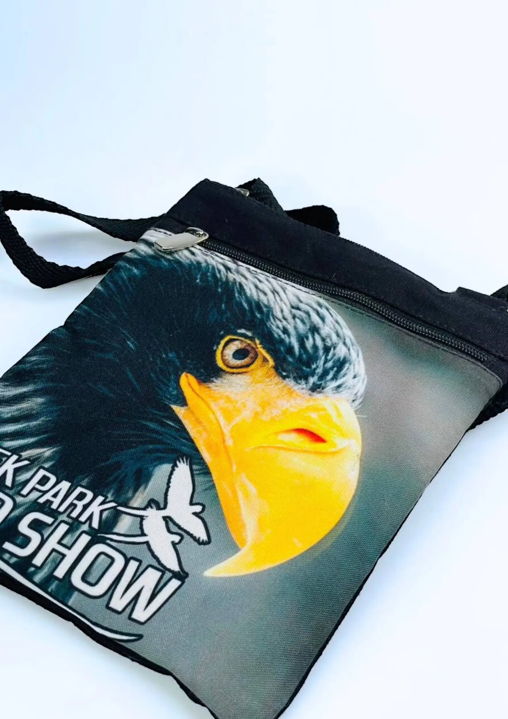 A stylish Creek Park Bird Show side bag with a black exterior and cloths straps. The bag has multiple compartments and pockets for storing essentials.