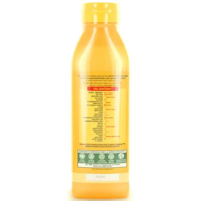 Close-up of a yellow Garnier Fructis Hair Food Banana Shampoo bottle with blue label and banana image. Rich, creamy shampoo being dispensed onto hand.