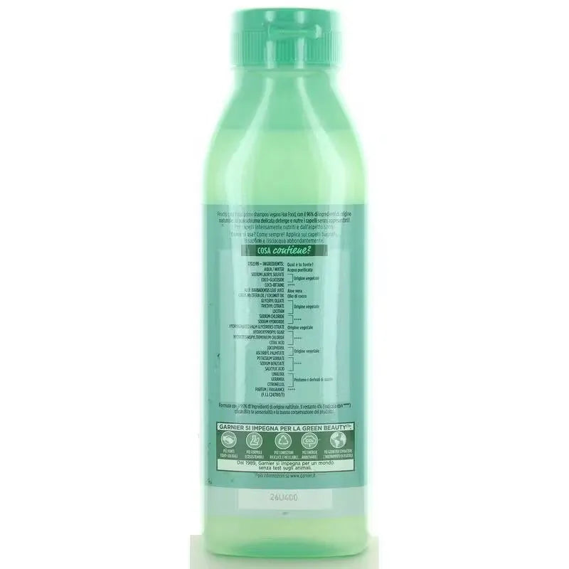 Close-up of Garnier Fructis Hair Food Shampoo bottle (350ml) with green accents and fruit image. Bottle dispenses clear shampoo onto hand.