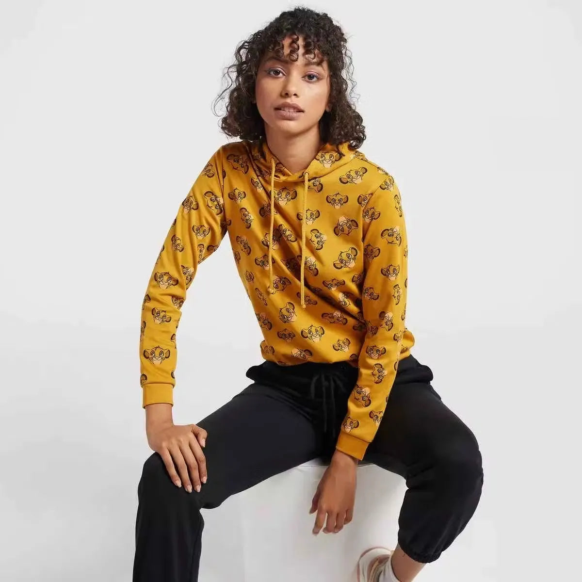 A woman wearing a hooded sweatshirt with a full-body print of The Lion King characters. Cozy up in style with the Max Lion King all-over print women's sweatshirt! Featuring a playful design and comfortable hoodie, this sweatshirt is perfect for casual wear. Shop now on Dubailisit!