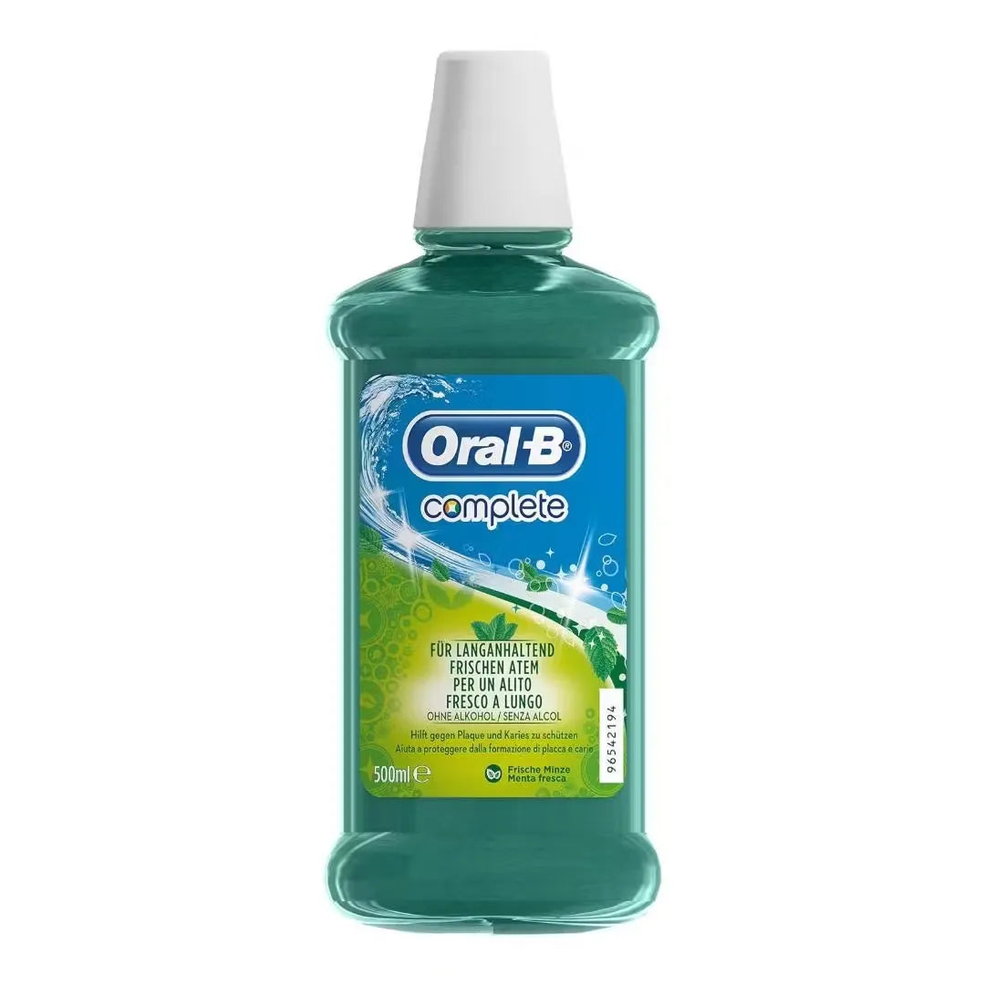 Close-up of a blue plastic bottle with a white pump dispenser labeled "Oral-B Complete Mint Mouthwash" (500ml). A splash of the minty-green liquid is shown pouring out.