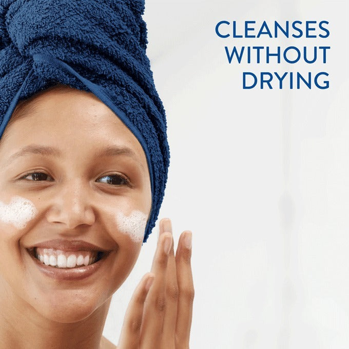 Close-up photo of a white Cetaphil Gentle Foaming Cleanser bottle with blue pump and label. Gentle foam being dispensed onto hand.