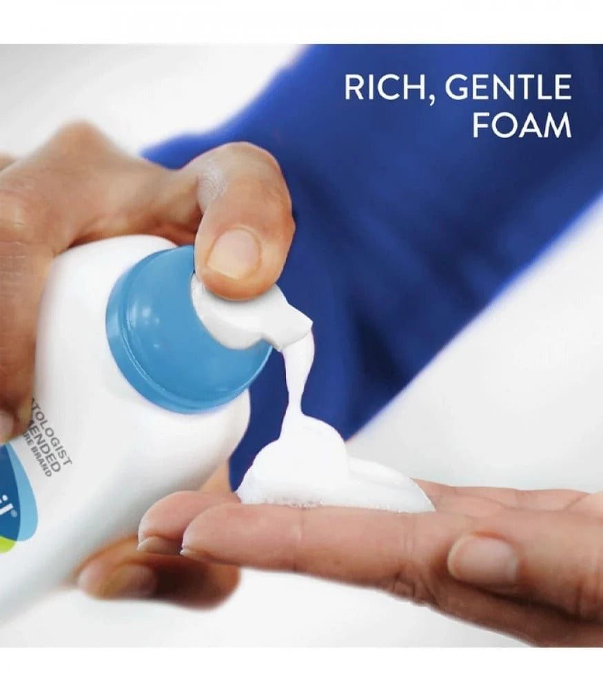 Close-up photo of a white Cetaphil Gentle Foaming Cleanser bottle with blue pump and label. Gentle foam being dispensed onto hand.