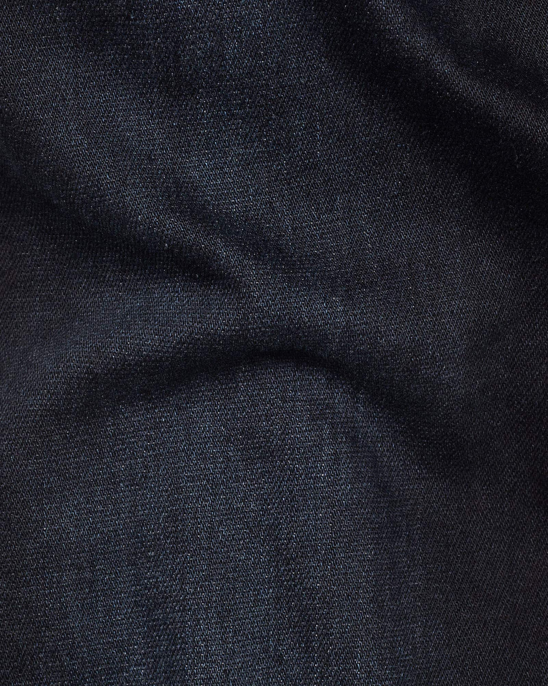 Close-up detail of dark blue denim fabric highlighting its soft texture and stretch features.