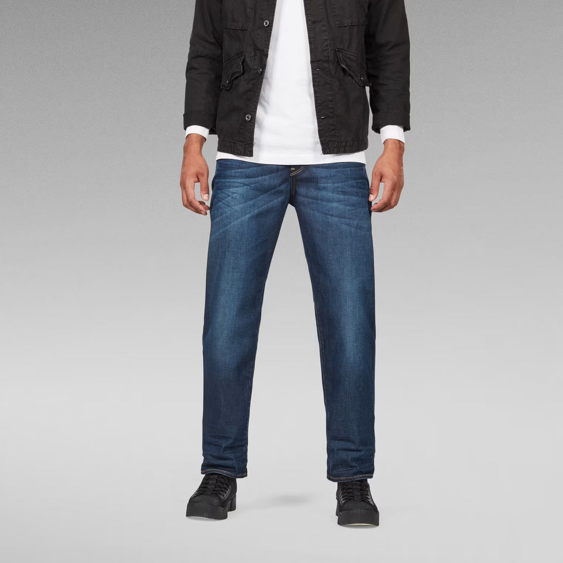 Lifestyle shot of dark blue relaxed fit jeans with a straight leg.