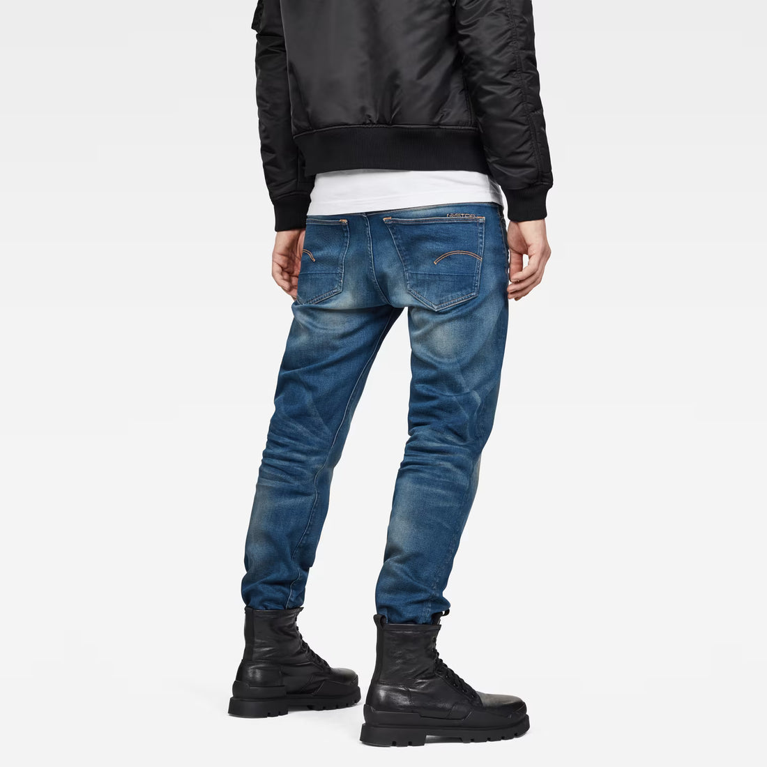 Back view of medium blue jeans showcasing a relaxed fit and distressed details on a white background.