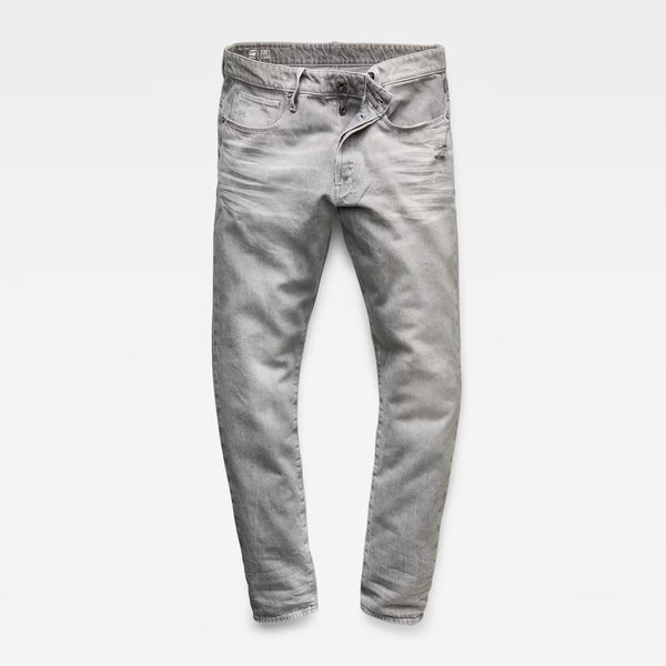 Front view of grey denim pants featuring a tapered fit and five pockets against a white background.