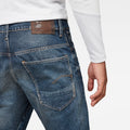 Detail close-up of dark blue jeans highlighting back pockets and brown label on a white background.