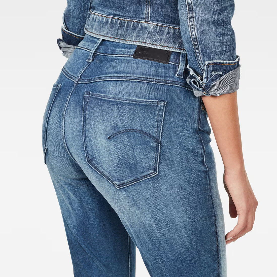 Detail close-up of medium blue skinny jeans highlighting back pocket design and faded areas.