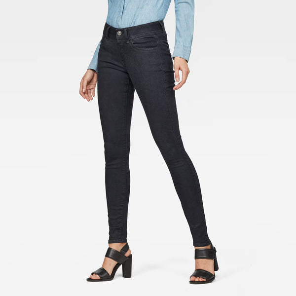 Lifestyle shot of black super skinny jeans with a mid-rise fit against a white background.