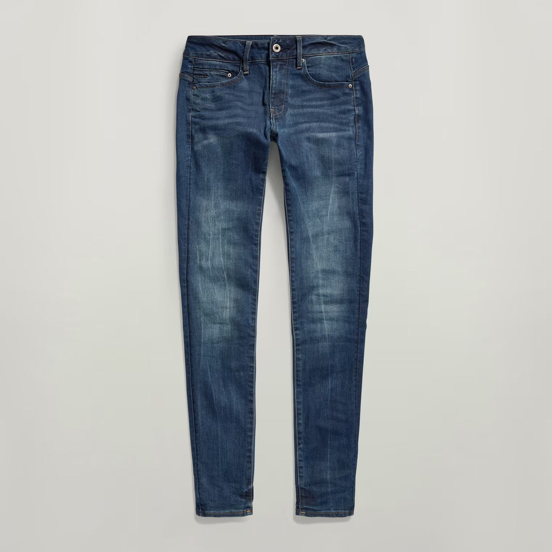 Close-up of dark blue skinny jeans with zipper detail on a white background.