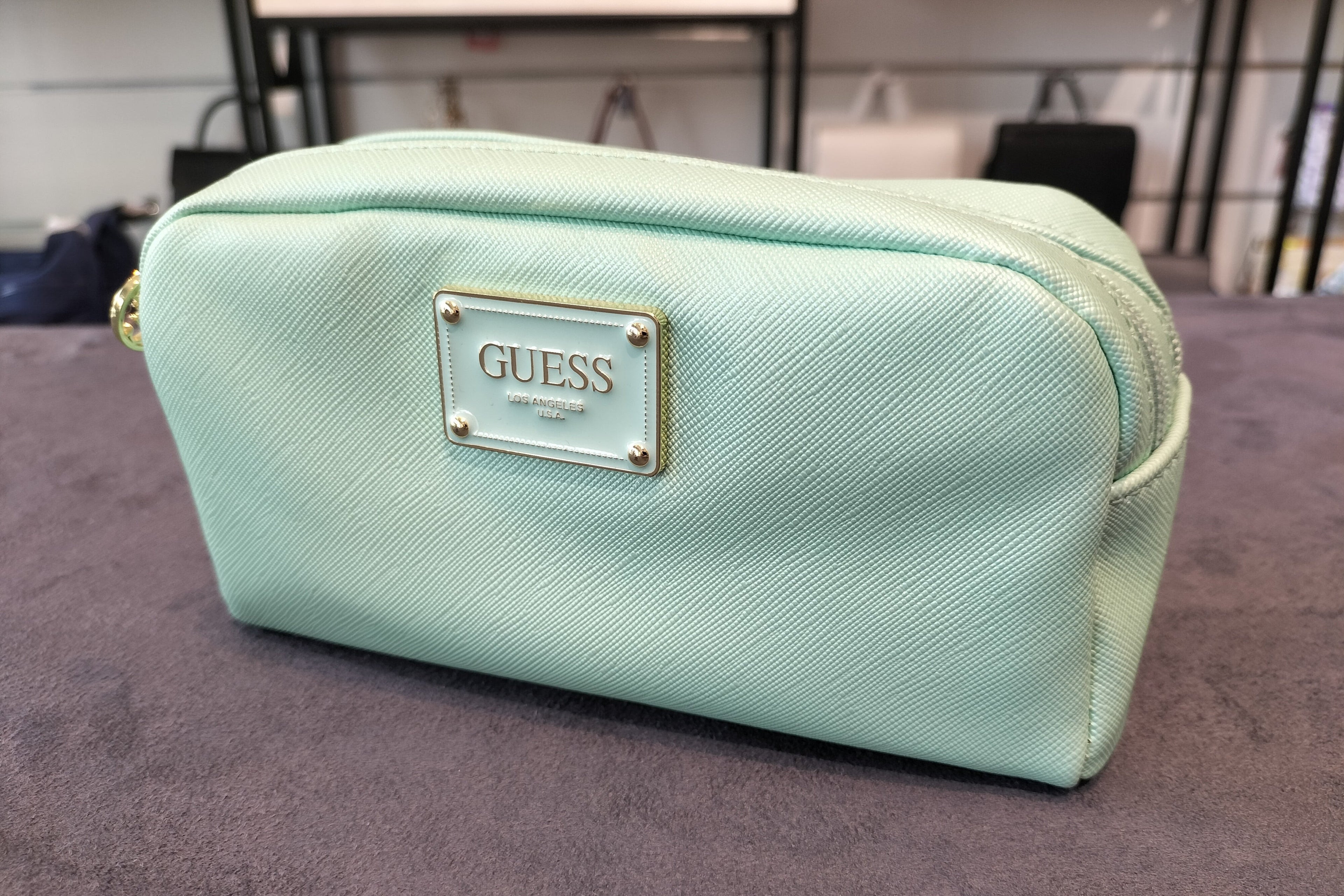 GUESS cosmetic bag featuring a metallic logo plaque and double zippers. PWBAHIP0273 - MNT