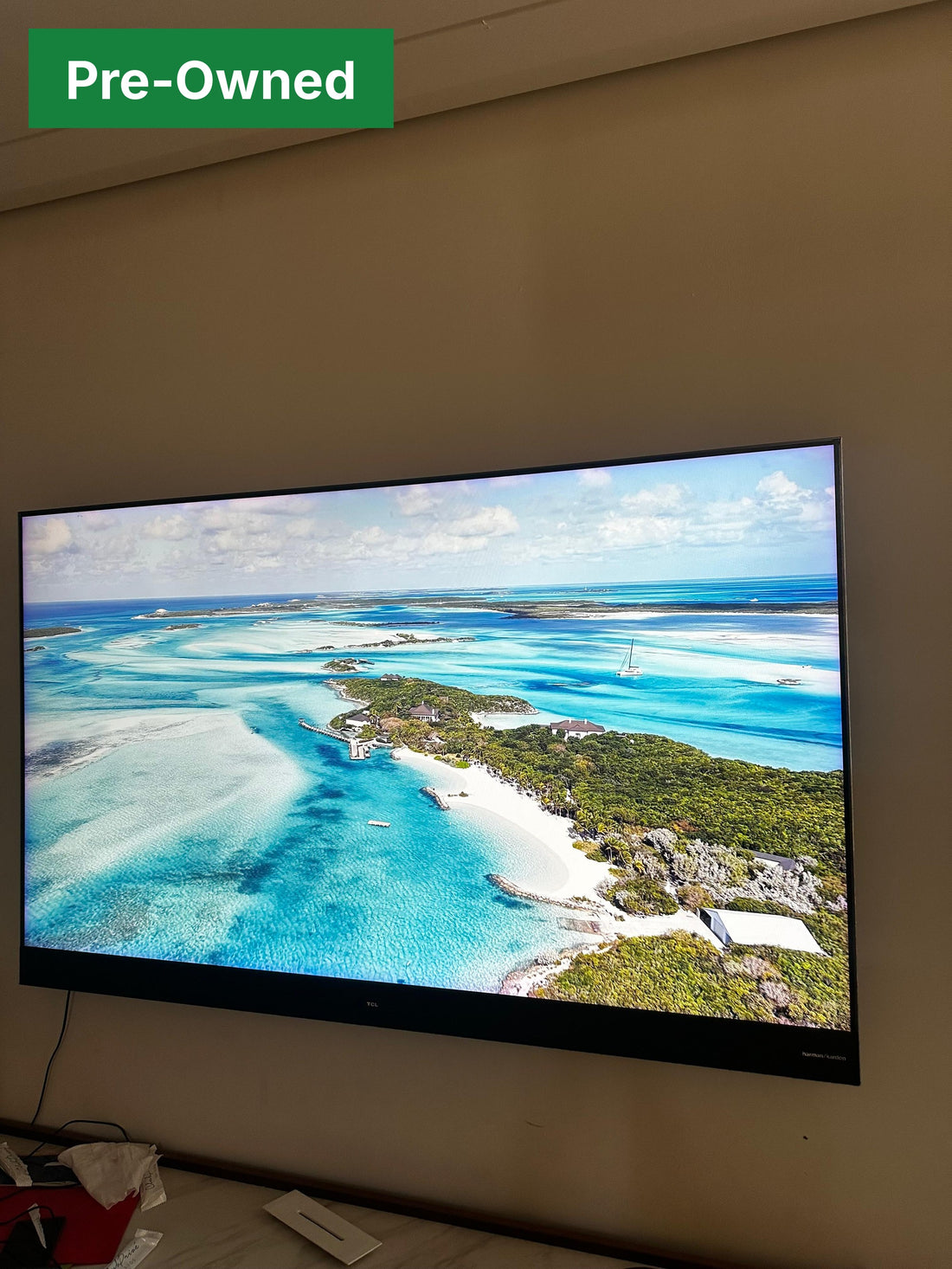 Real photo of the pre-owned TCL 65 inch 65X4US TV wall-mounted and switched on